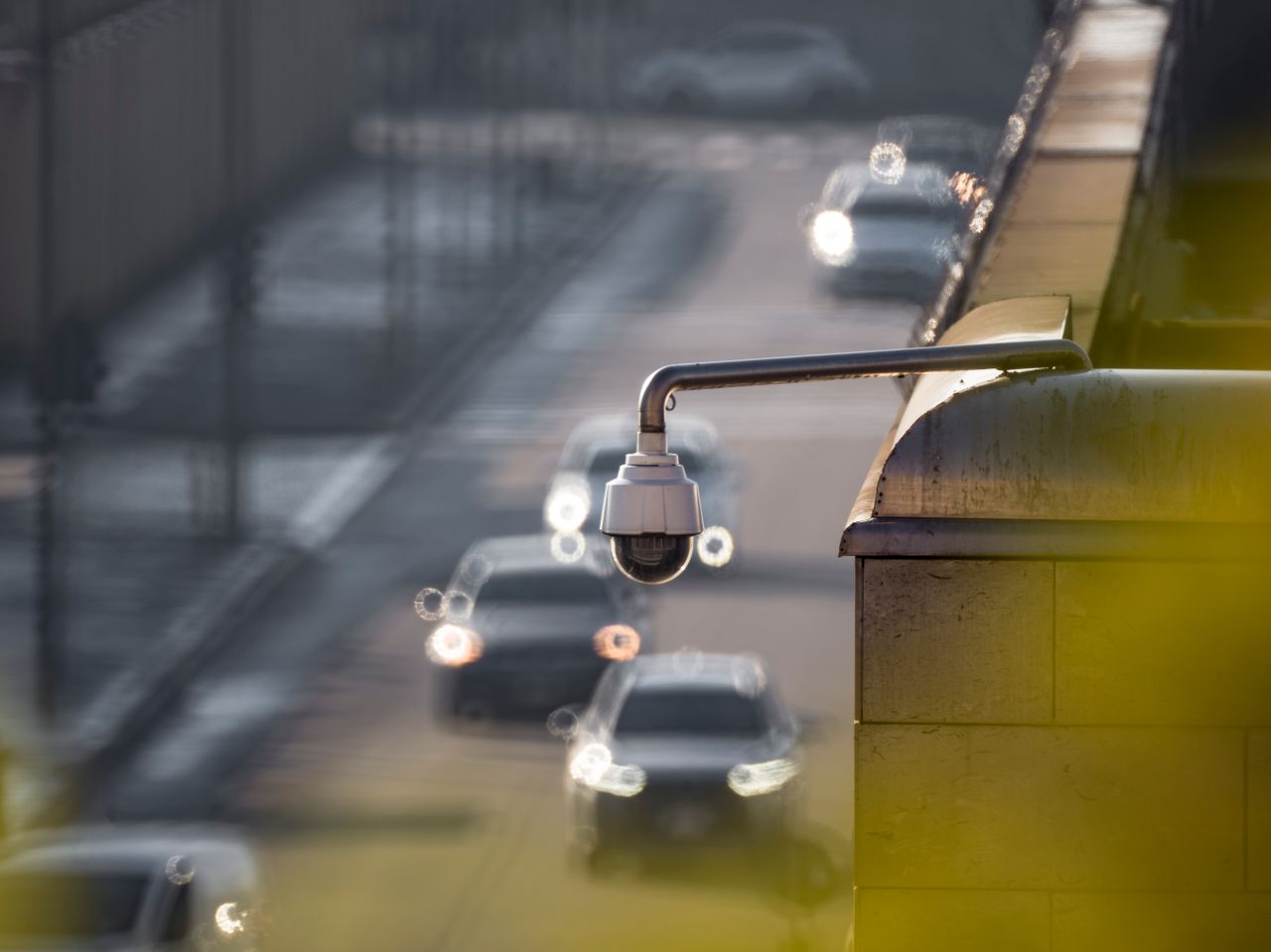 The Art of Drawing Readers In: Your attractive post title goes here CCTV camera monitoring city traffic on a busy road with blurred vehicles in the background.